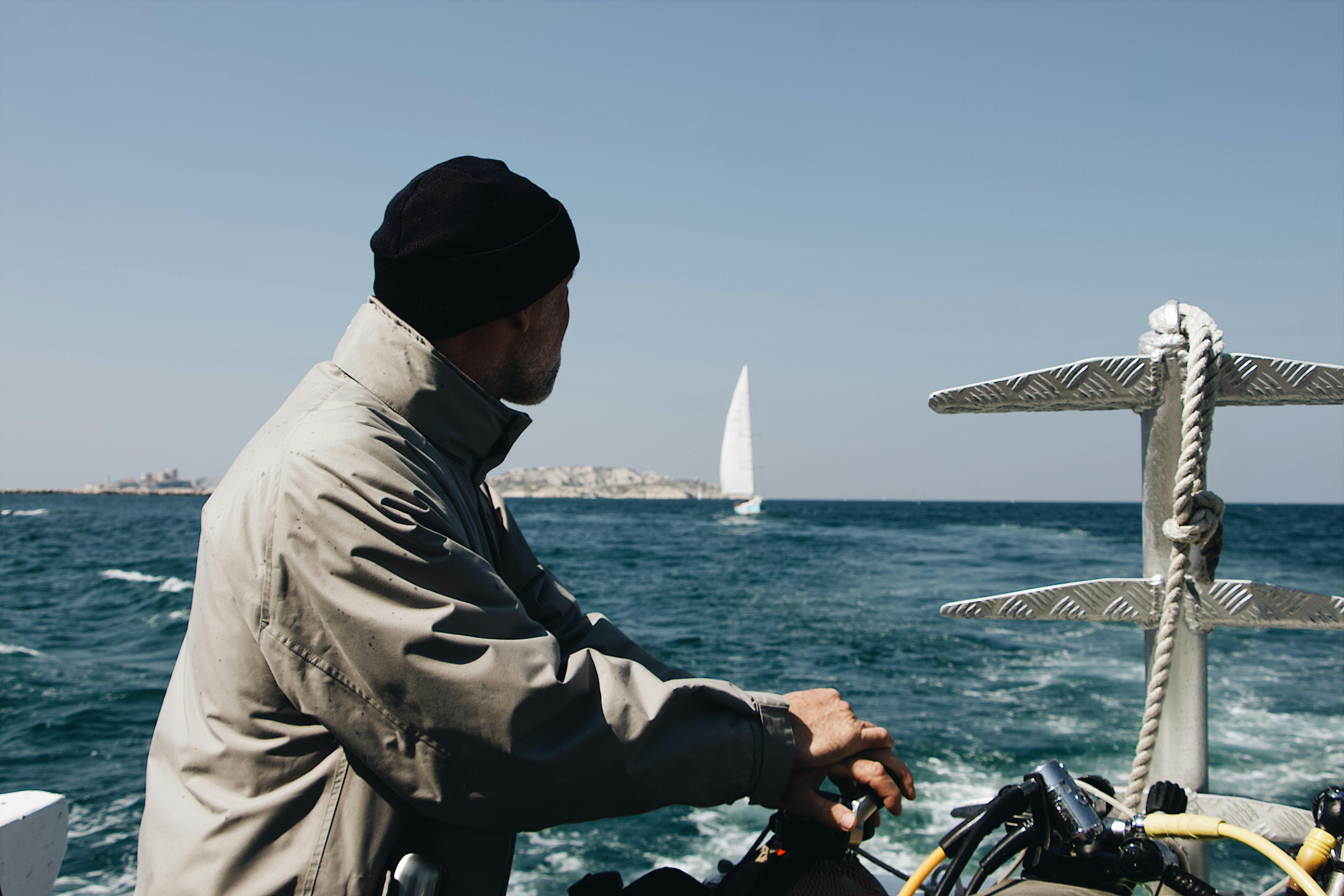 man wearing grey jacket in a watercraft out at sea